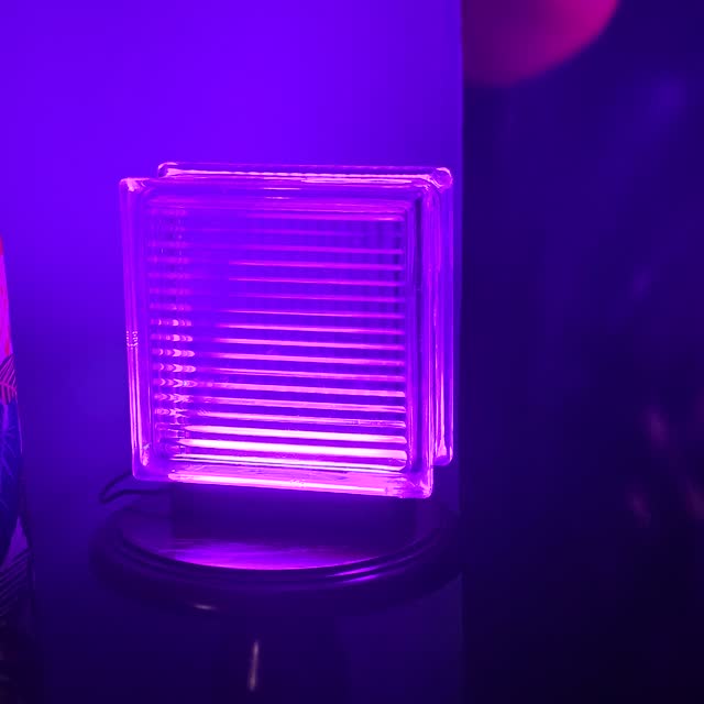Purple lamp on a side table next to a patterned curtain